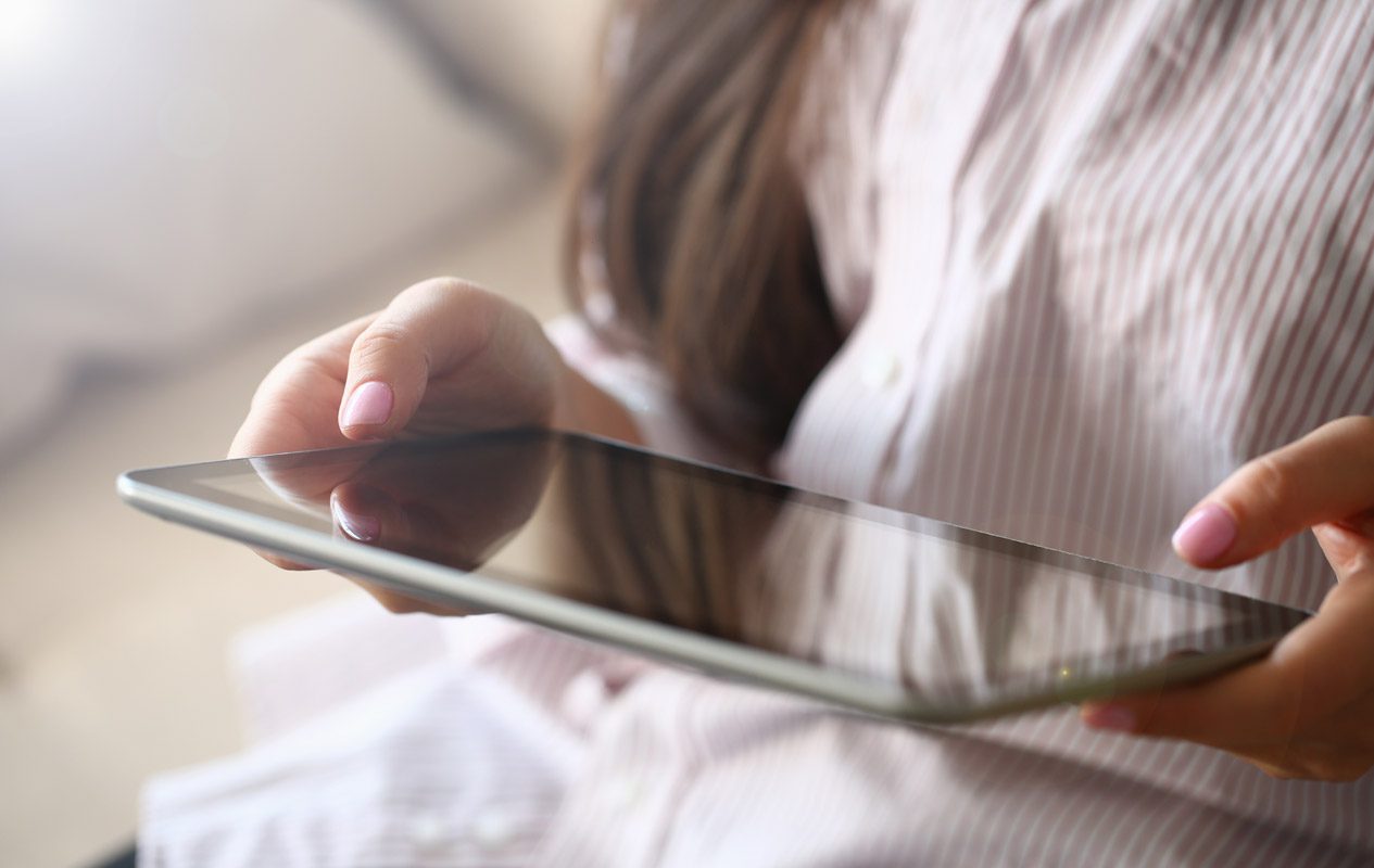 Female Hand Holds Tablet In Home Setting While